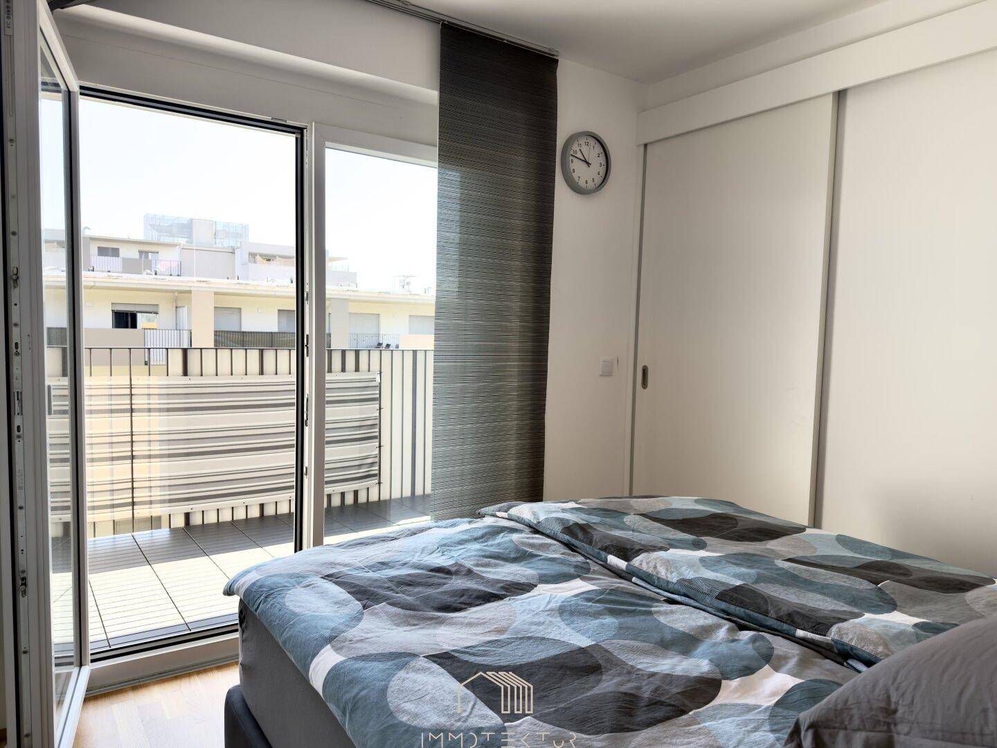 Schlafzimmer mit Doppelbett, Schiebetürenschrank und direktem Zugang zum Balkon.