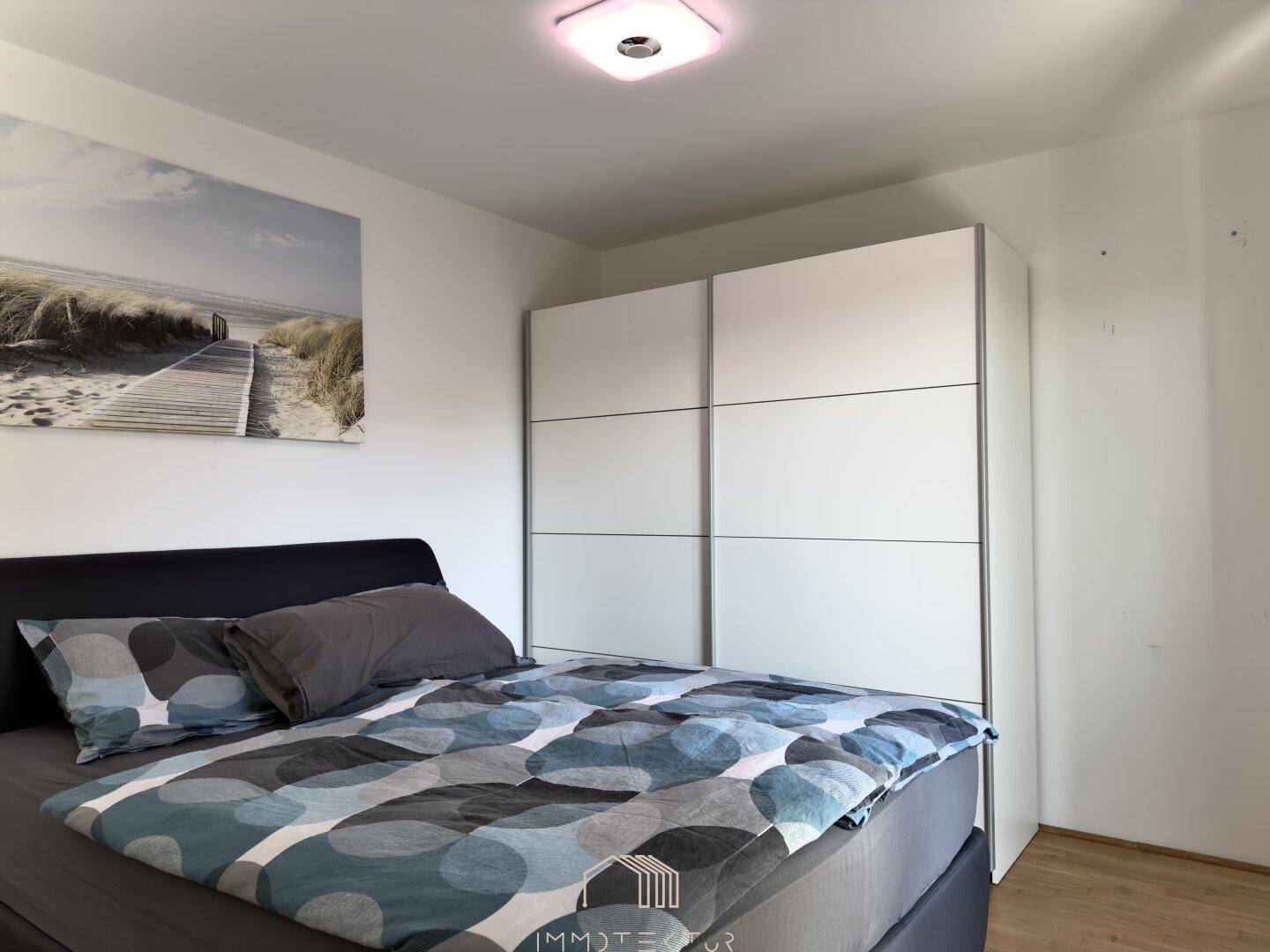 Gemütliches Schlafzimmer mit Doppelbett und großem weißen Kleiderschrank.