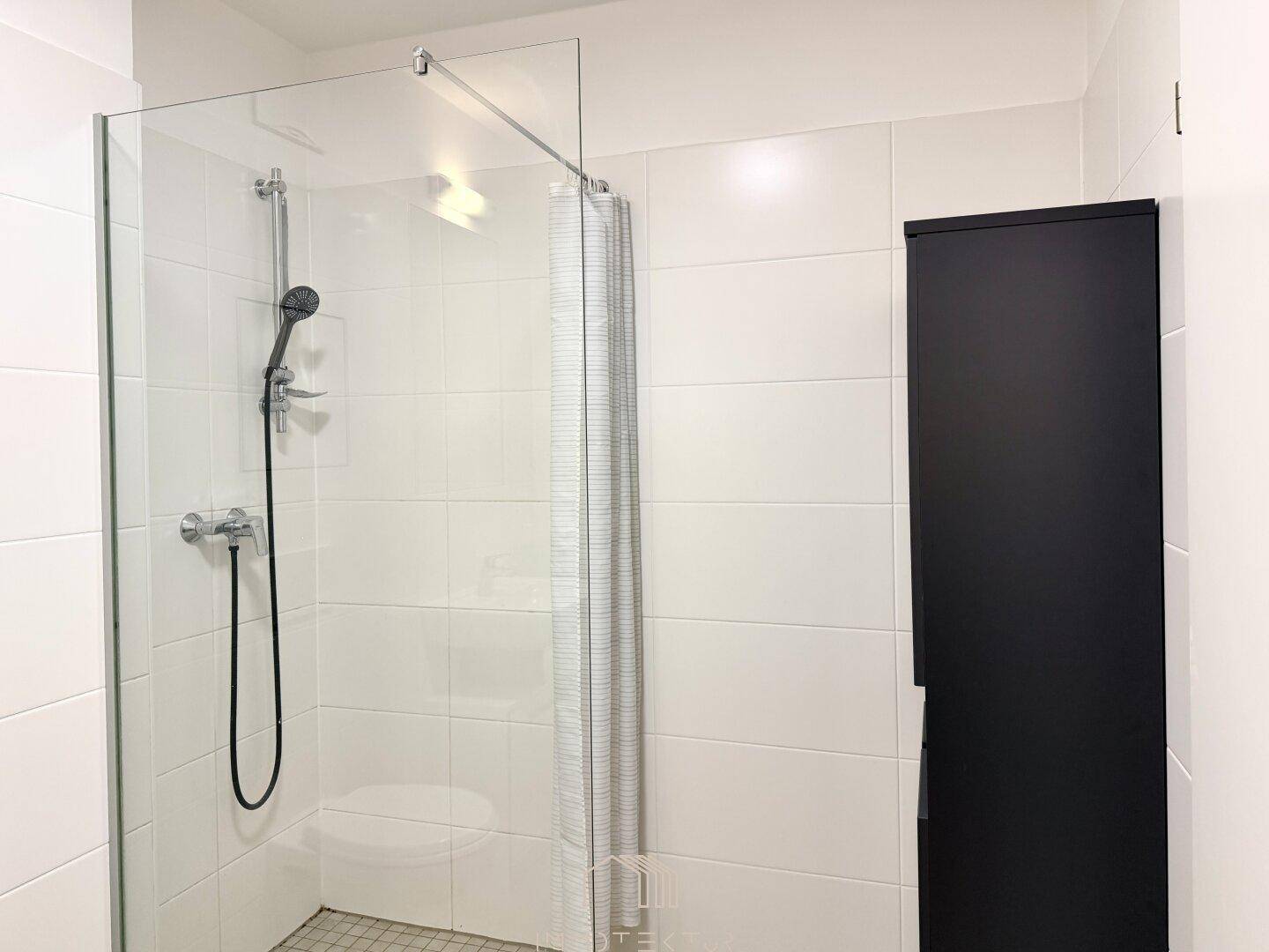 Modernes Badezimmer mit weiß gefliesten Wänden und ebenerdiger Dusche.