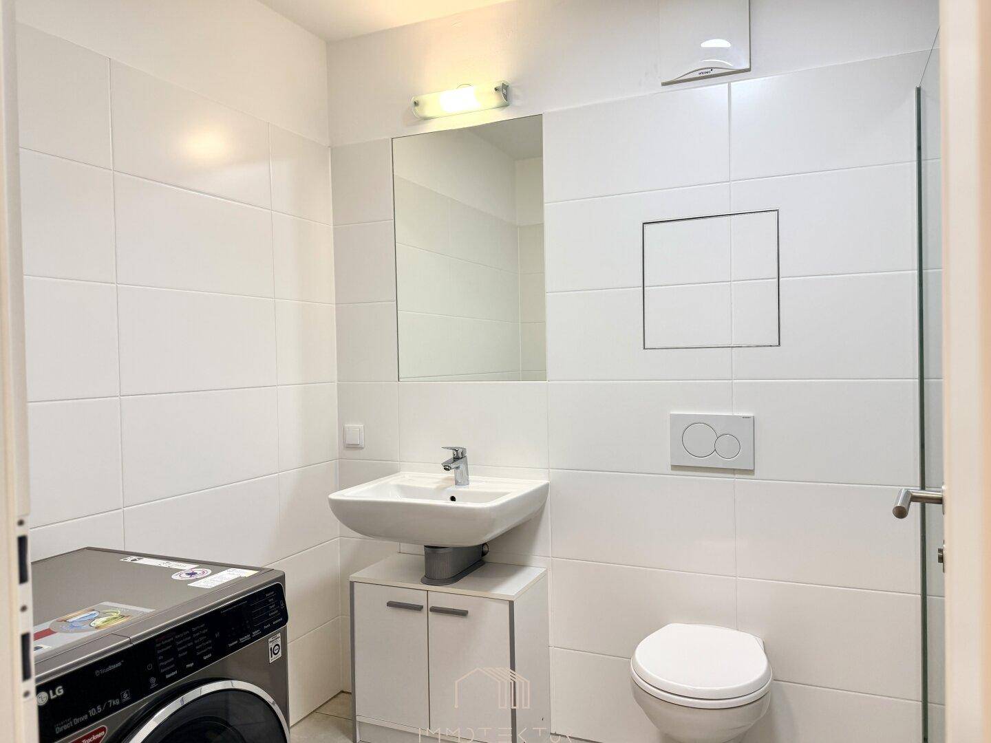 Helles Badezimmer mit Waschbecken, Toilette und Waschmaschine.