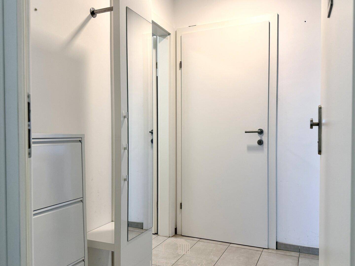 Heller Flur mit Schuhschrank und großem Spiegel.