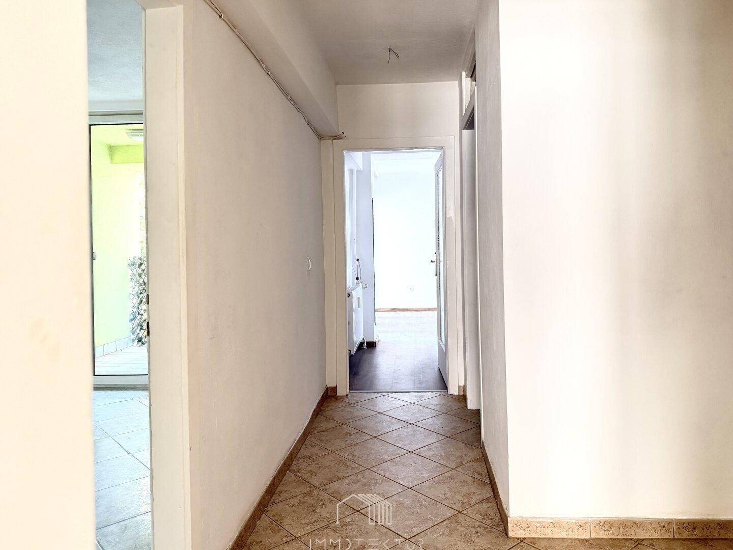 Langer Flur mit Fliesenboden und Zugang zu verschiedenen Räumen der Wohnung.