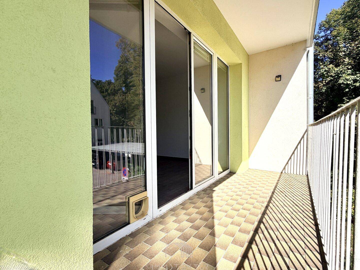 Sonniger Balkon mit Fliesenboden und Schiebetür, die viel Licht in den Innenraum lässt.