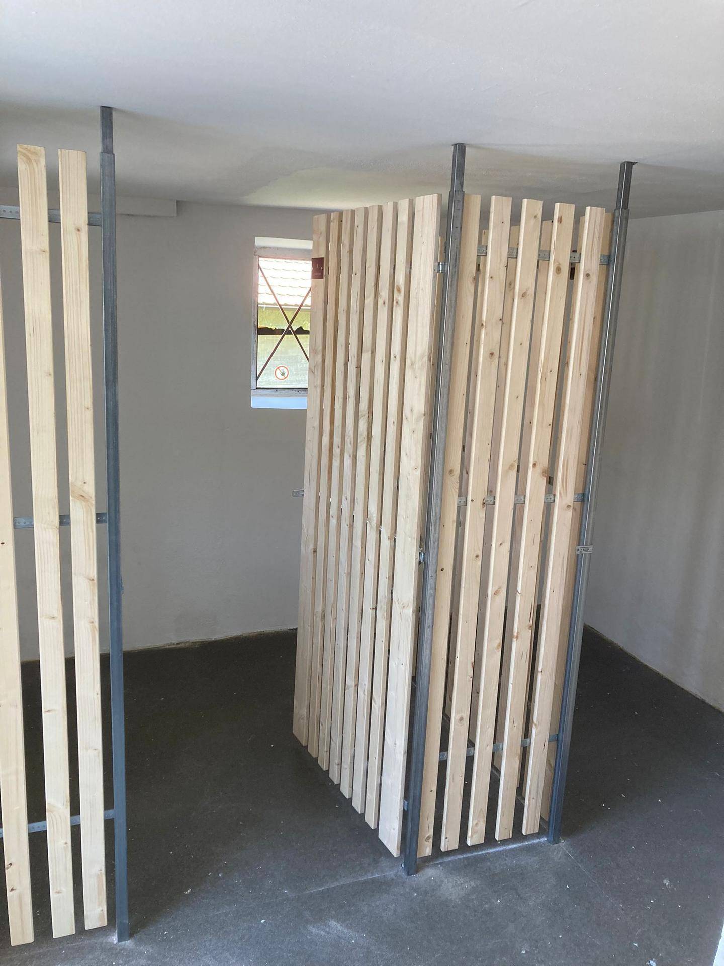 Lagerraum im Keller mit Holzabtrennungen und kleinem Fenster für natürliche Belüftung und Tageslicht.