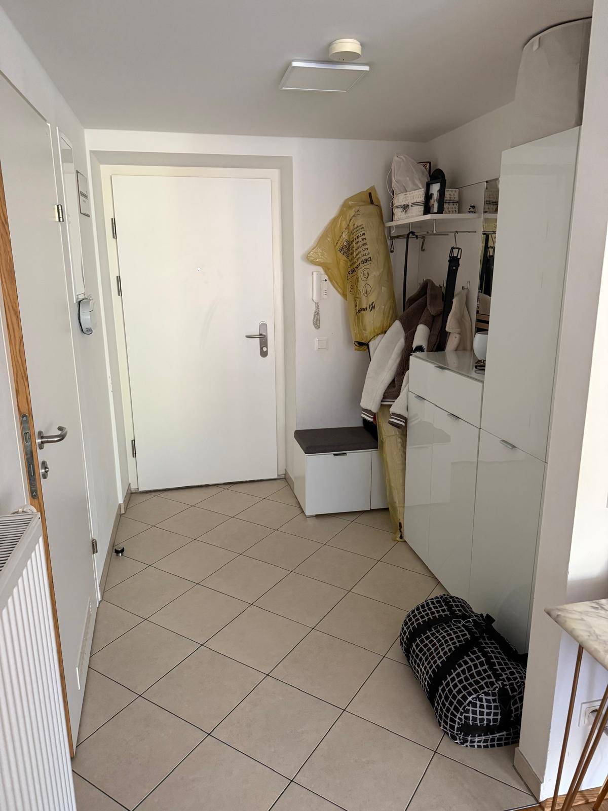 Heller Eingangsbereich mit Fliesenboden, weißer Garderobe und praktischem Stauraum.