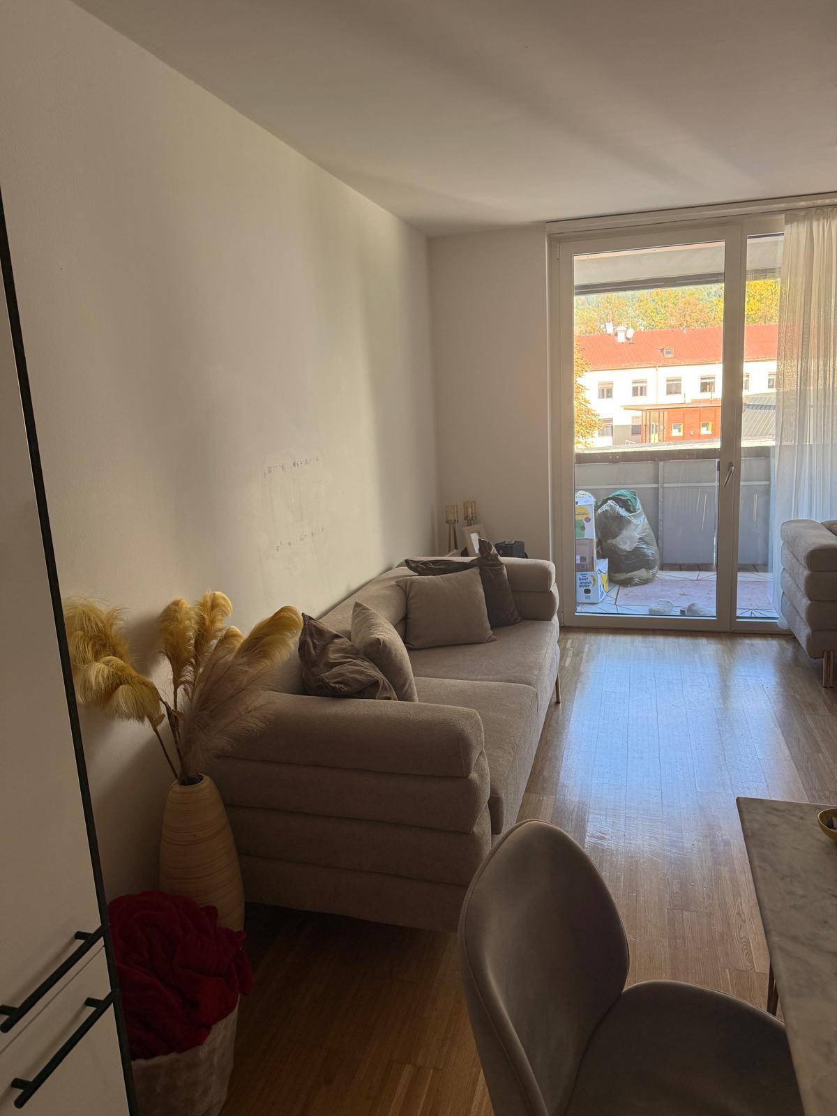 Heller Wohnbereich mit bequemem Sofa, Parkettboden und direktem Zugang zum Balkon.