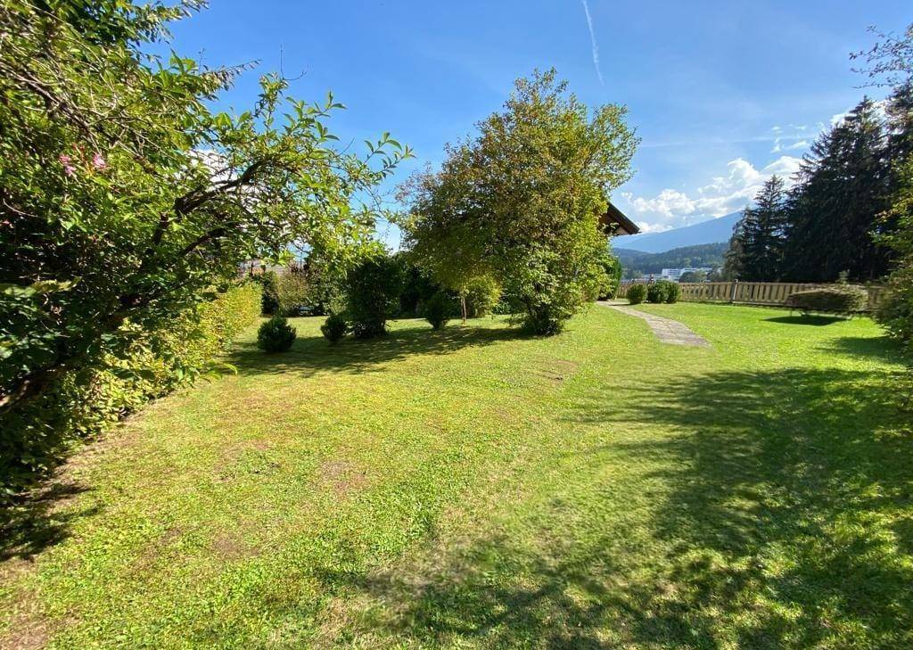 Weitläufiger Gartenbereich mit altem Baumbestand und Blick auf die umliegende Landschaft und Berge.