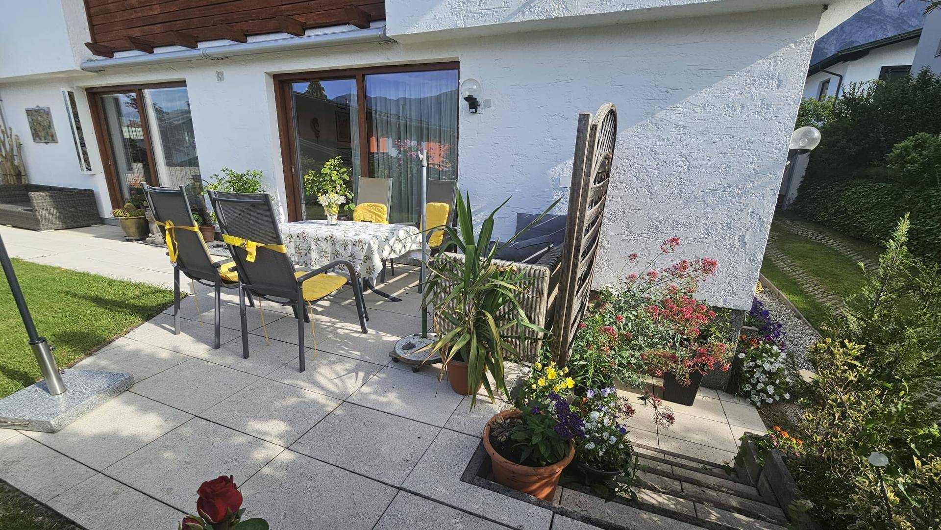 Helle Terrasse mit modernen Gartenmöbeln und direktem Zugang zum grünen Gartenbereich, ideal für entspannte Stunden im Freien.