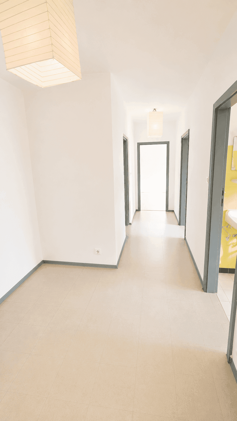 Heller Flur mit hellem Bodenbelag und mehreren Türen, die zu anderen Räumen führen.