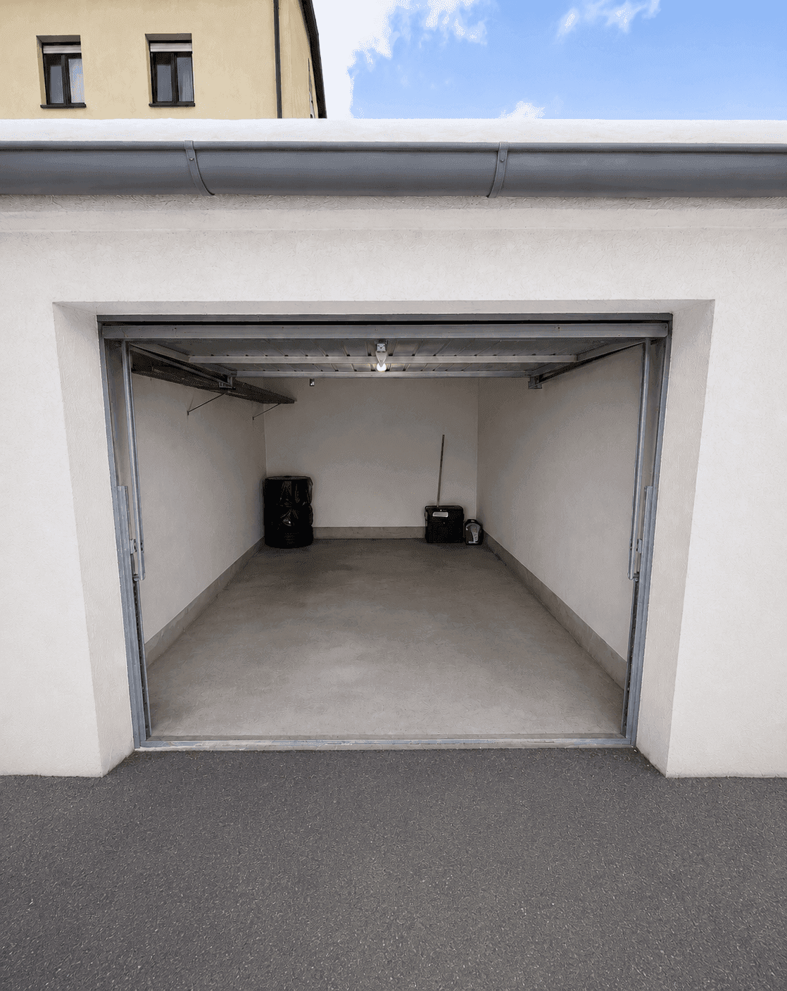 Leere Einzelgarage mit offenem Tor und Betonboden, bereit zur Nutzung.