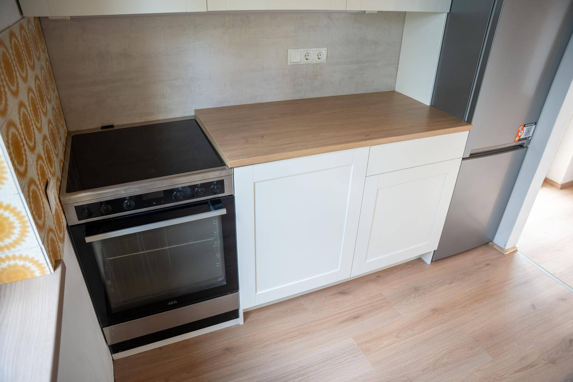 Detailansicht der Küche mit weißer Schrankfront, Holz-Arbeitsplatte und integriertem Backofen.
