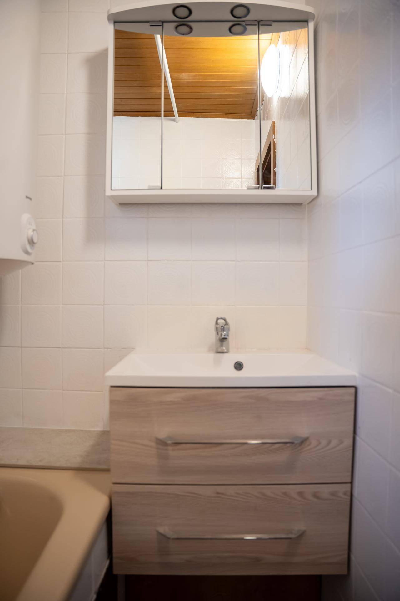 Badezimmer mit modernem Waschtischunterschrank, Einzelwaschbecken und Spiegelschrank.