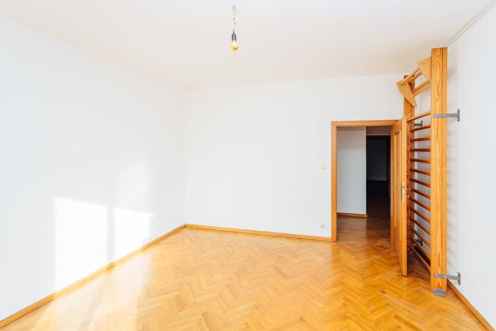 Helles Zimmer mit Fischgrätparkett und Sprossenwand, ideal für Sport oder Kinderzimmer.