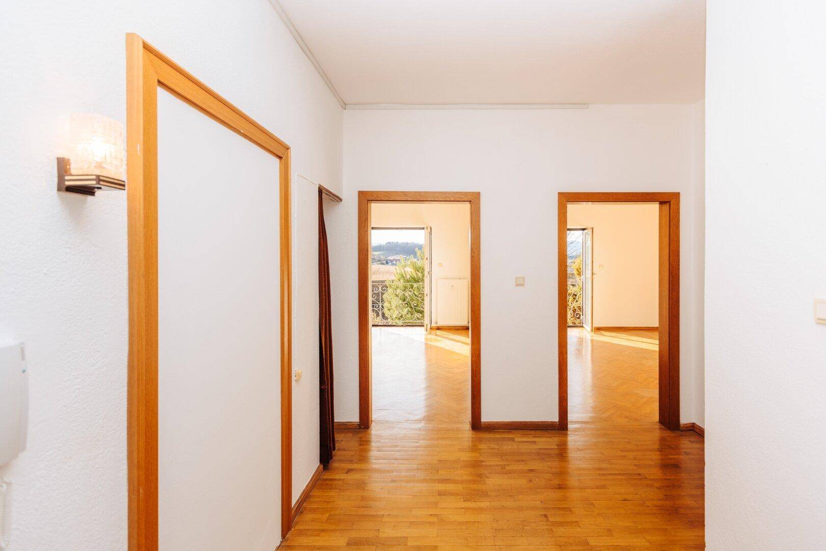 Heller Flur mit Parkettboden und mehreren Holztüren, die zu verschiedenen Räumen führen.