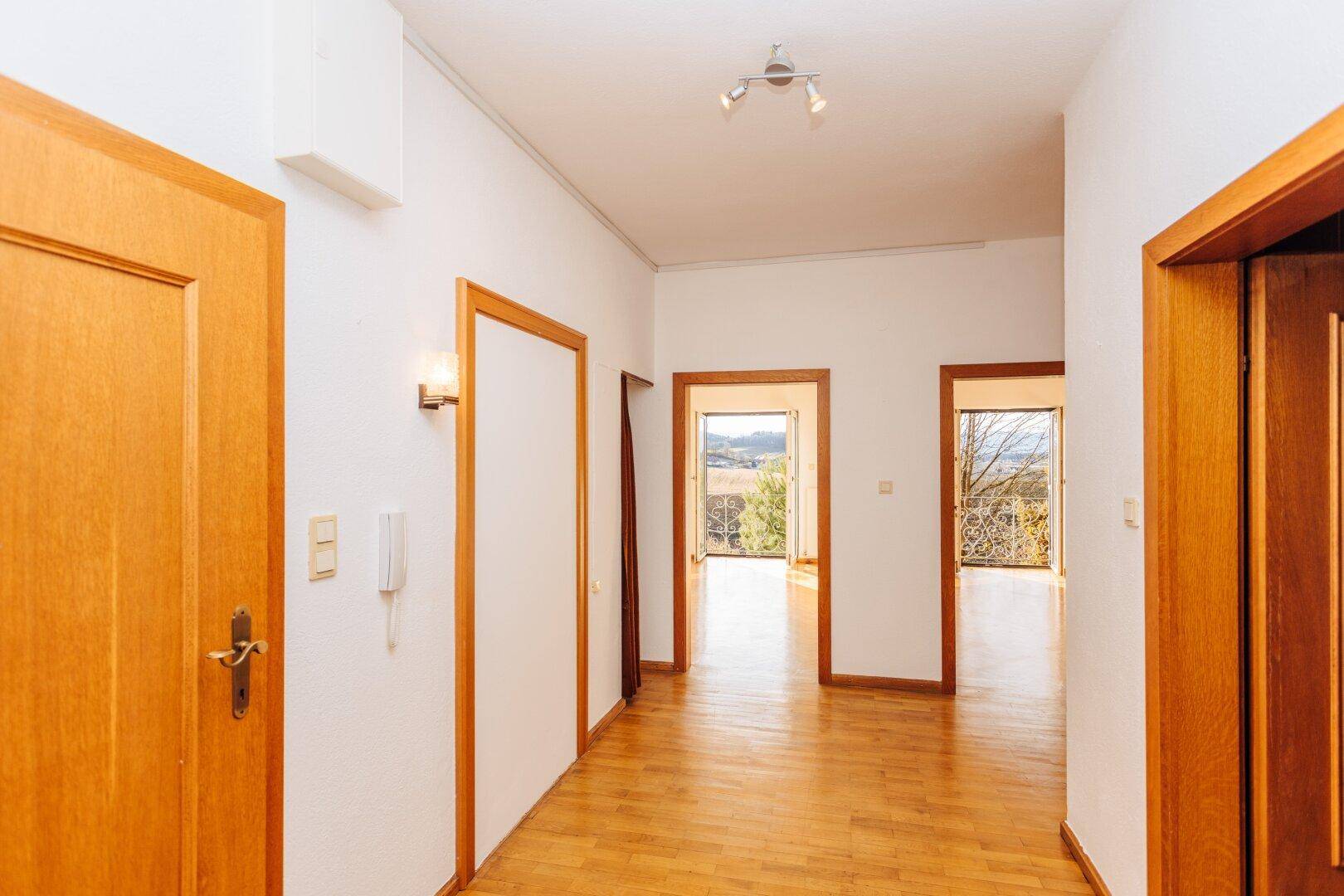 Geräumiger Flur mit Holzboden und mehreren Türen, der zu weiteren hellen Räumen führt.