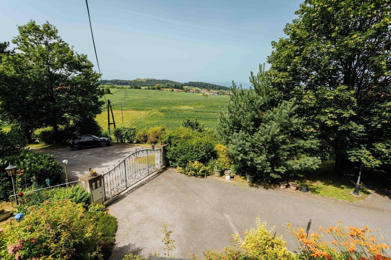 Blick von oben auf die Zufahrt des Anwesens und die umliegende weite Landschaft.
