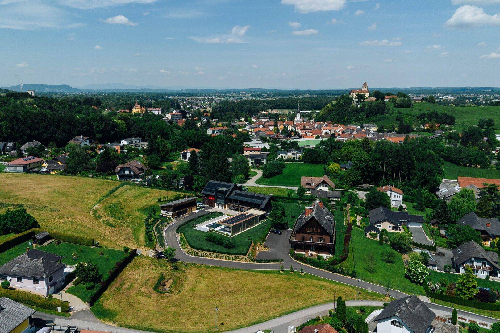 Panoramablick aus der Vogelperspektive auf eine idyllische Wohngegend mit viel Grün und einem historischen Schloss.