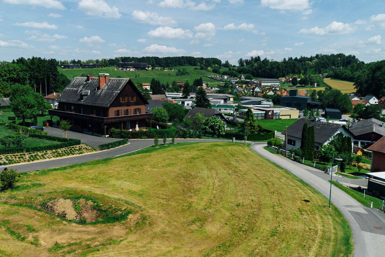 Grundstück in einer ländlichen Wohngegend mit Blick auf traditionelle Häuser und grüne Umgebung.