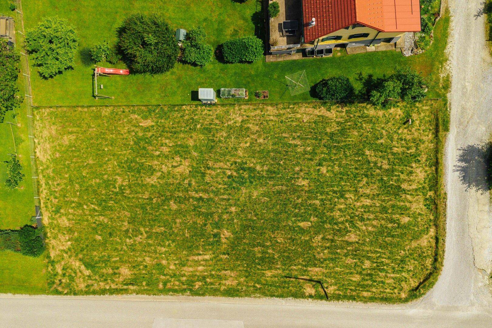 Senkrechte Luftaufnahme eines großen, rechteckigen Grundstücks mit angrenzenden Häusern und Straßen.