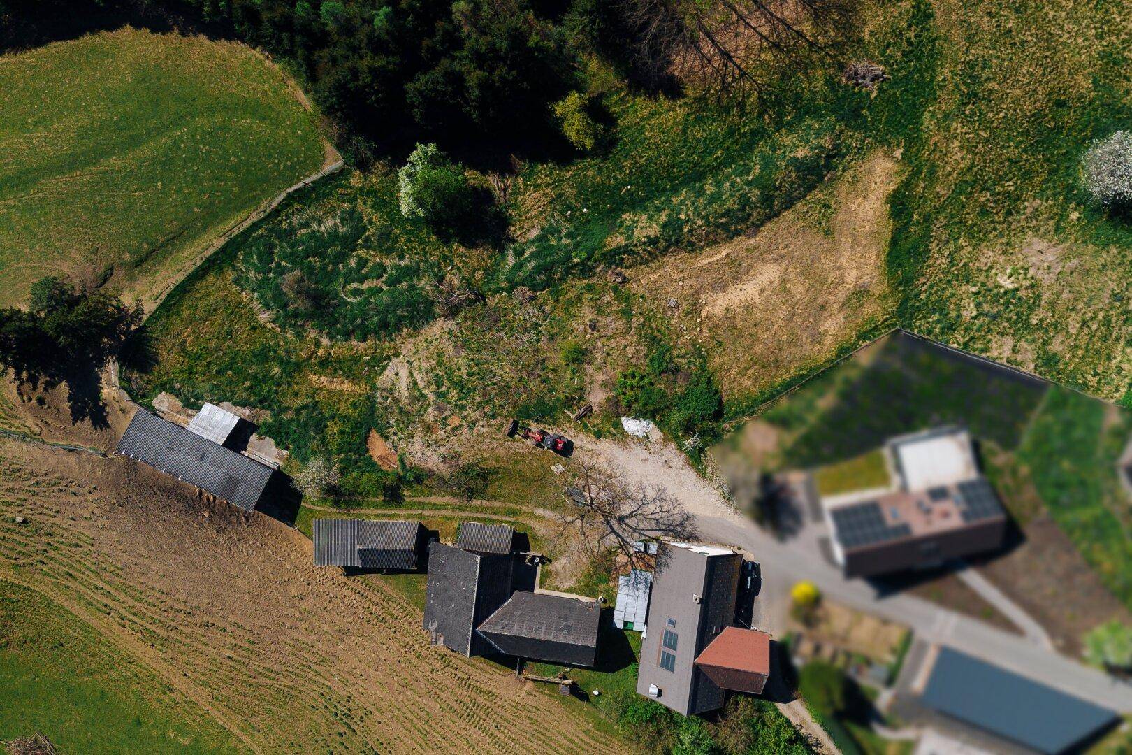Blick von oben auf ein Anwesen mit Gebäuden, einem Auto und angrenzenden Feldern und Wegen.