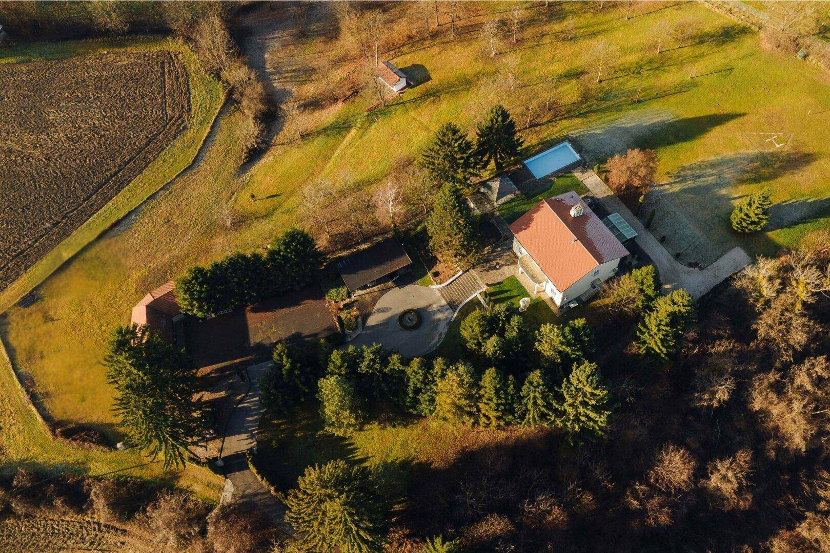 Luftaufnahme des Anwesens mit Haupthaus, Pool und weitläufiger Grünfläche.