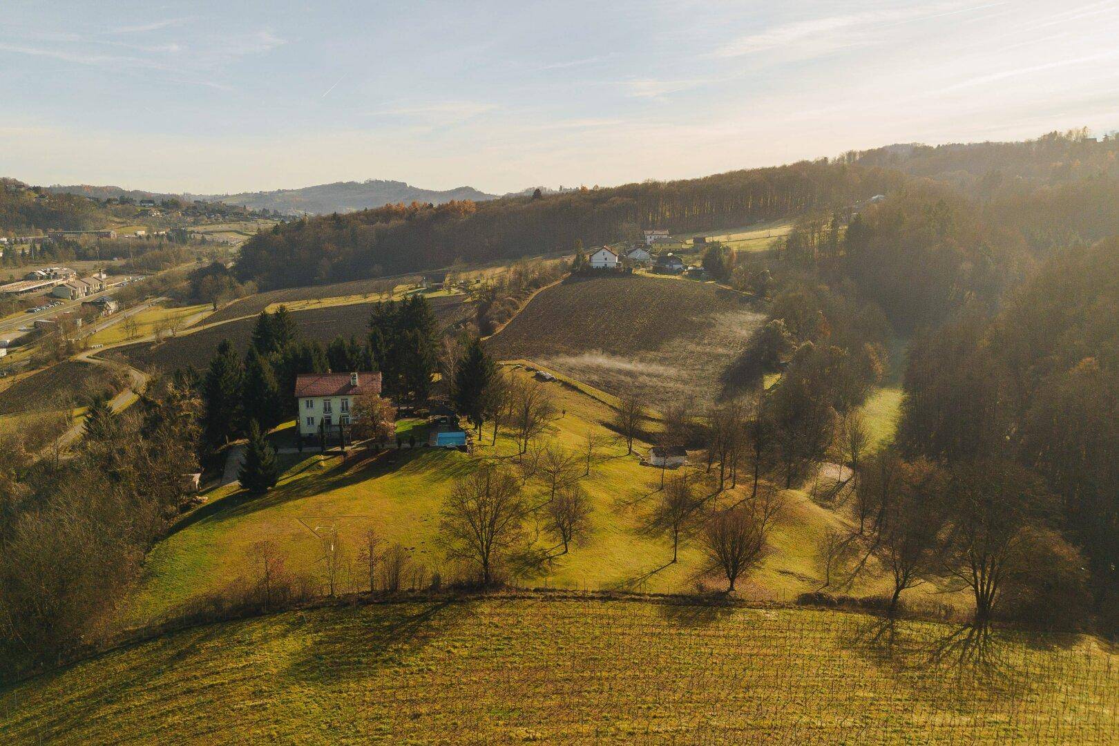 Luftaufnahme des Hauses mit Pool und weitläufigen Feldern in sonniger Umgebung.