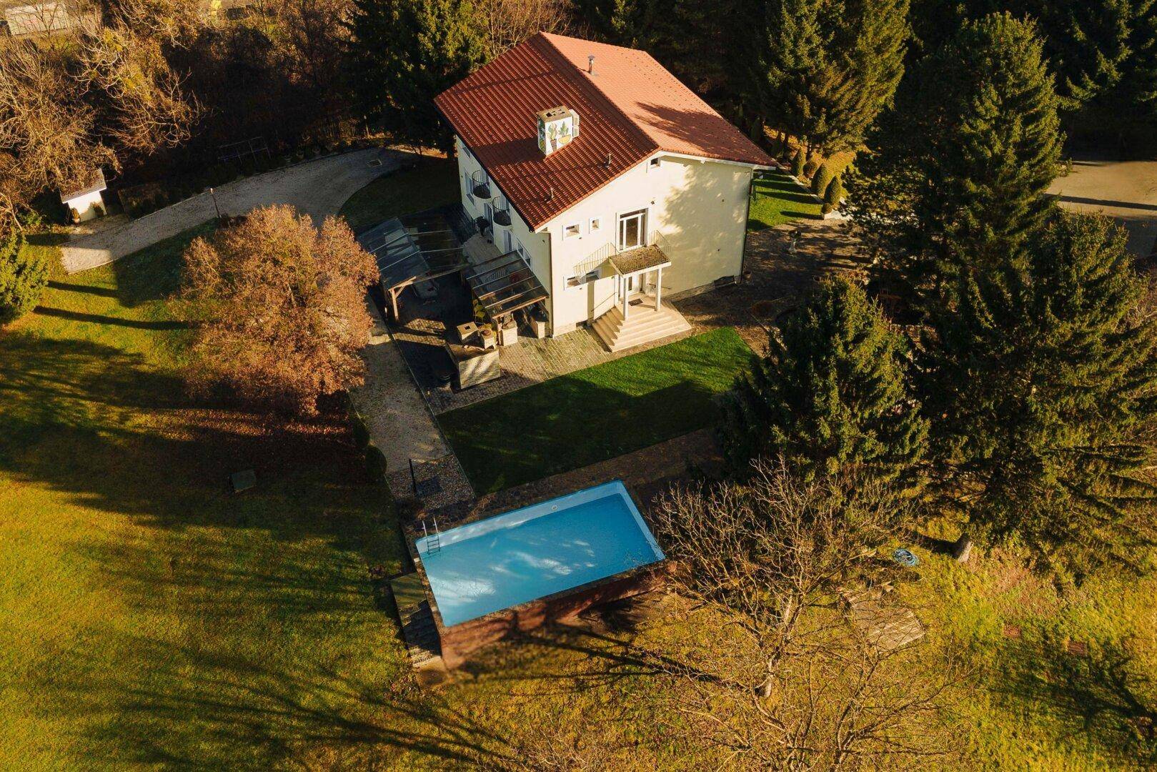 Draufsicht auf das Hauptgebäude mit rotem Dach und dem angrenzenden Swimmingpool.
