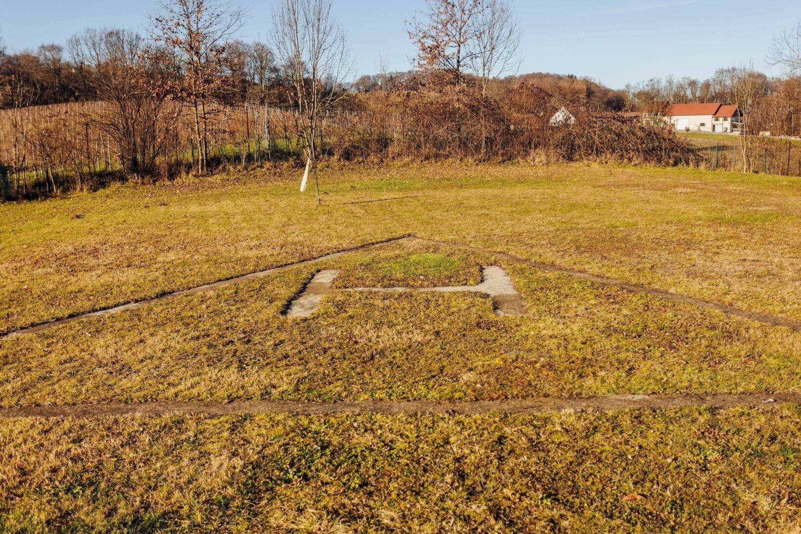 Leeres Grundstück mit sichtbaren Fundamentumrissen, bereit für eine neue Bebauung.
