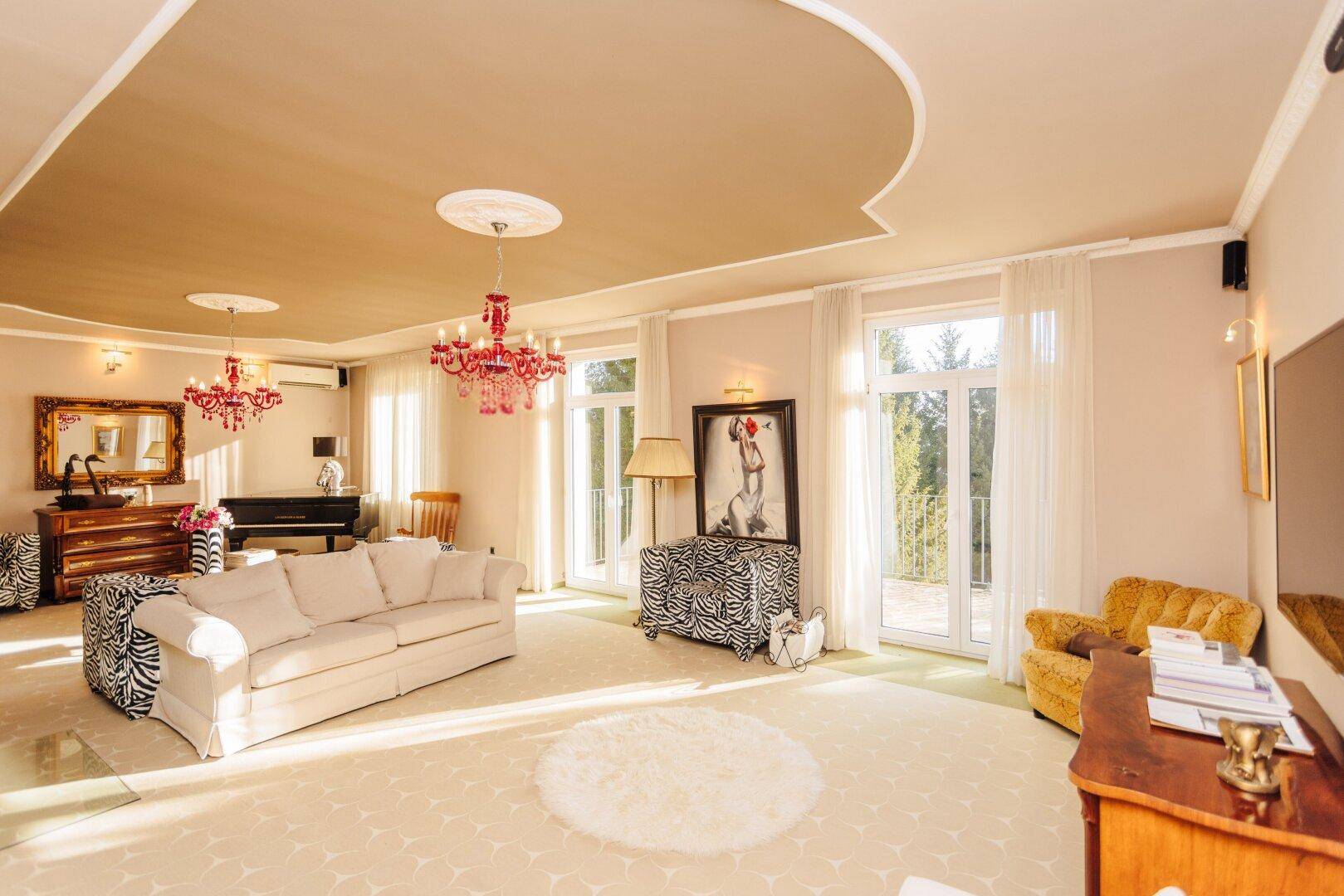 Geräumiges Wohnzimmer mit Flügel, bequemen Sofas und großen Fenstern für viel Licht.