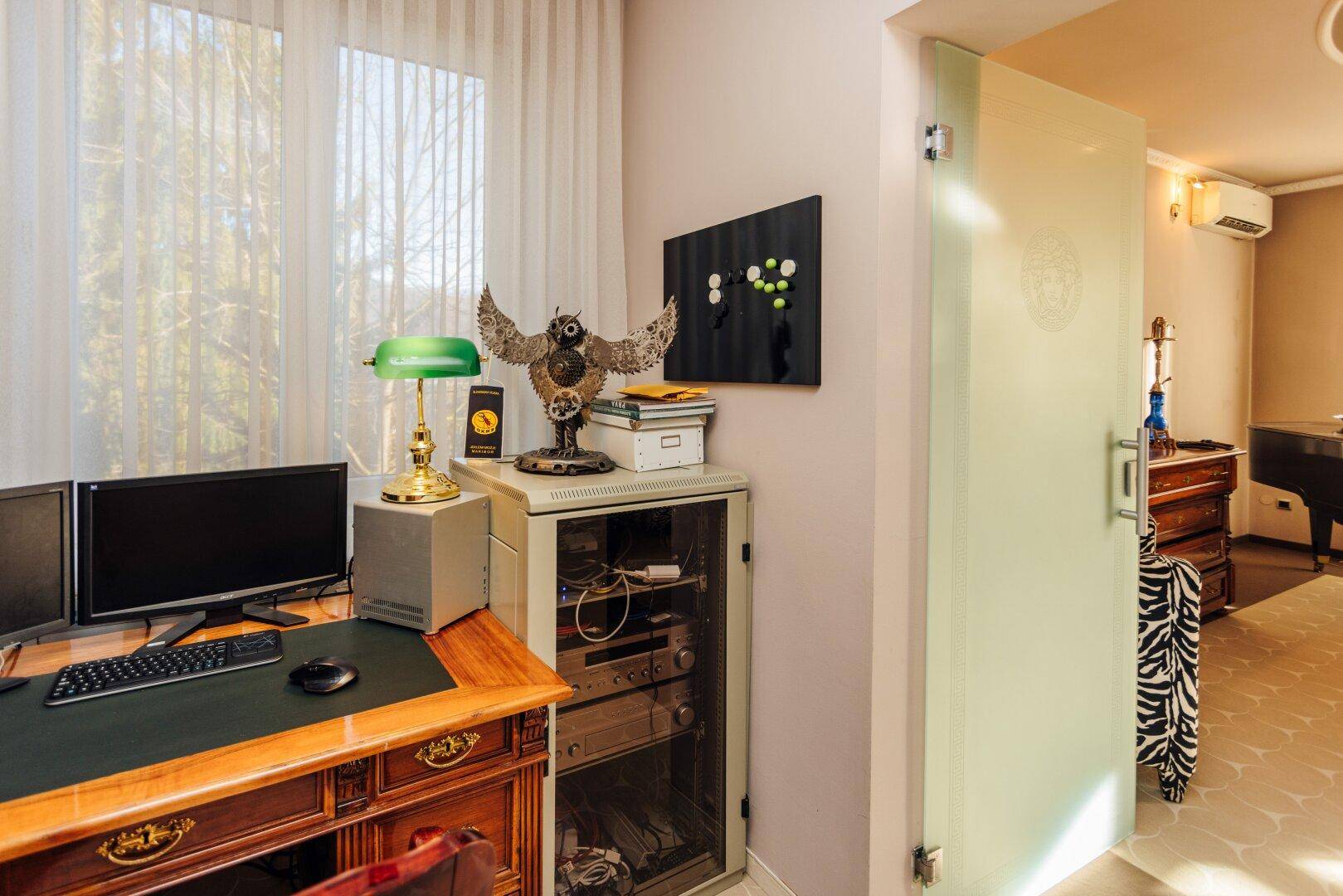 Funktionales Büro mit Schreibtisch, Computern und einer modernen Glastür.