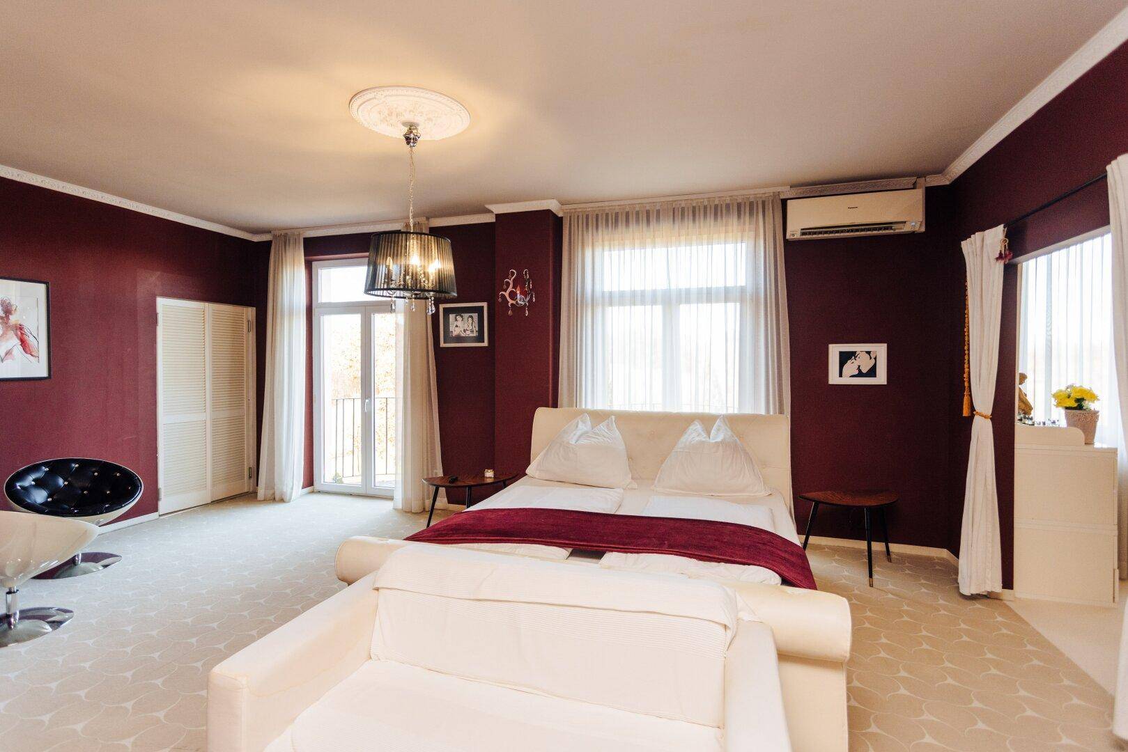 Helles Schlafzimmer mit roten Wänden, großem Bett und direktem Zugang zum Balkon.