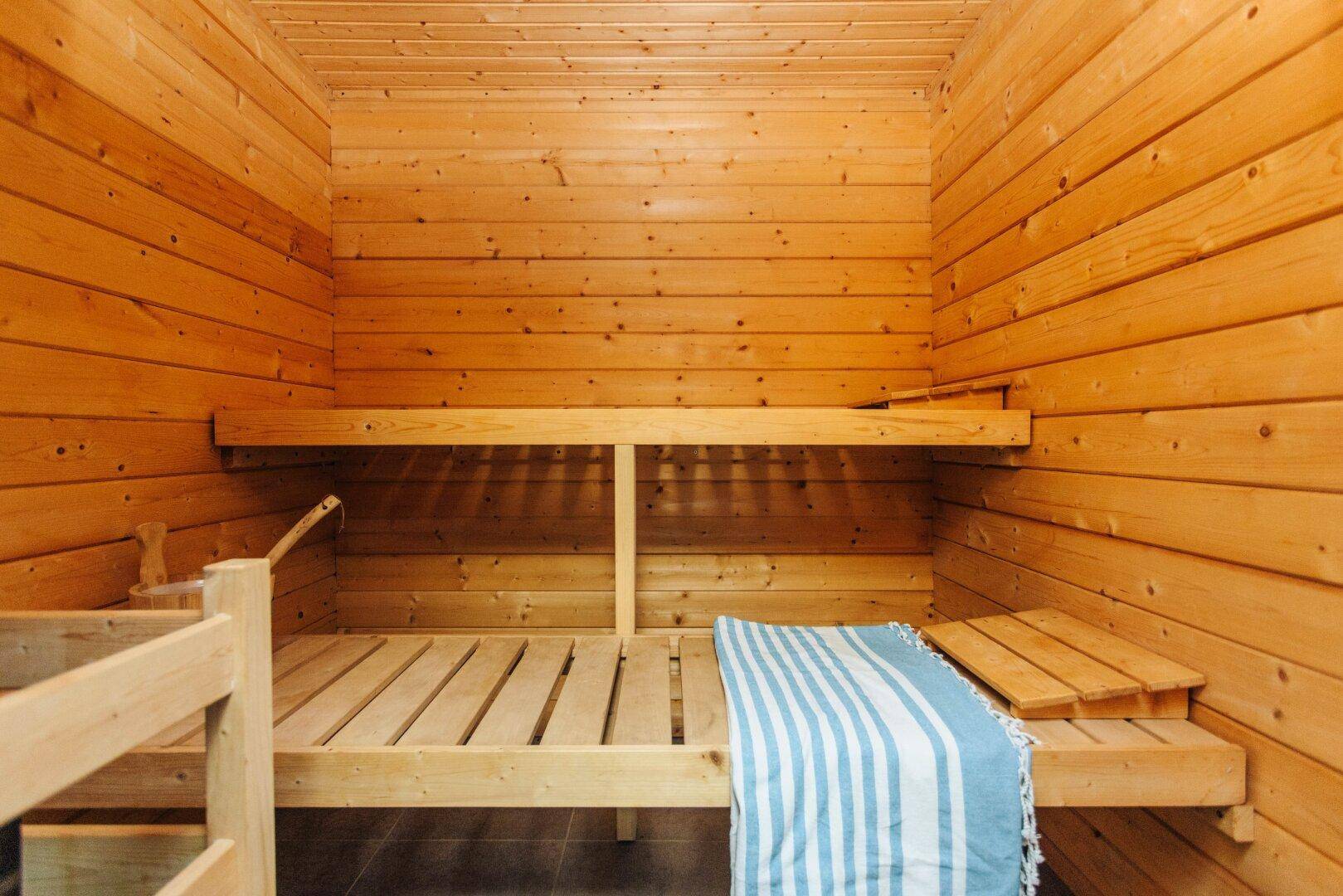 Traditionelle Holzsauna mit Bänken und Handtuch, bereit zur Entspannung.