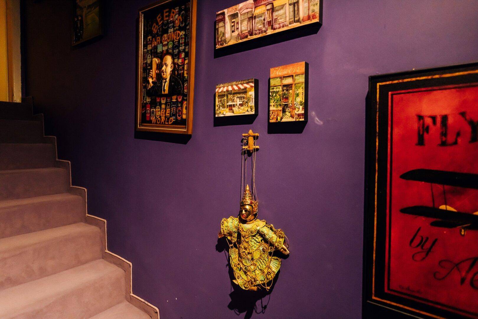 Treppenhaus mit lila Wänden und einer Sammlung von Kunstwerken.