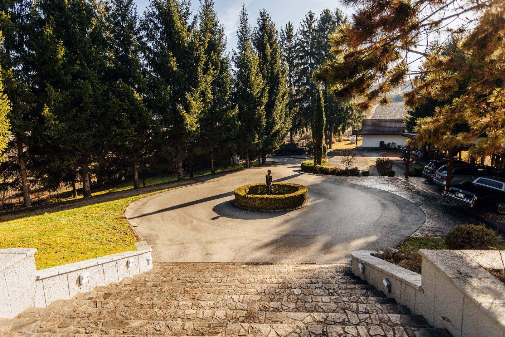 Eindrucksvolle Freitreppe führt zum Haus, umgeben von einem kreisförmigen Vorplatz mit Brunnen.