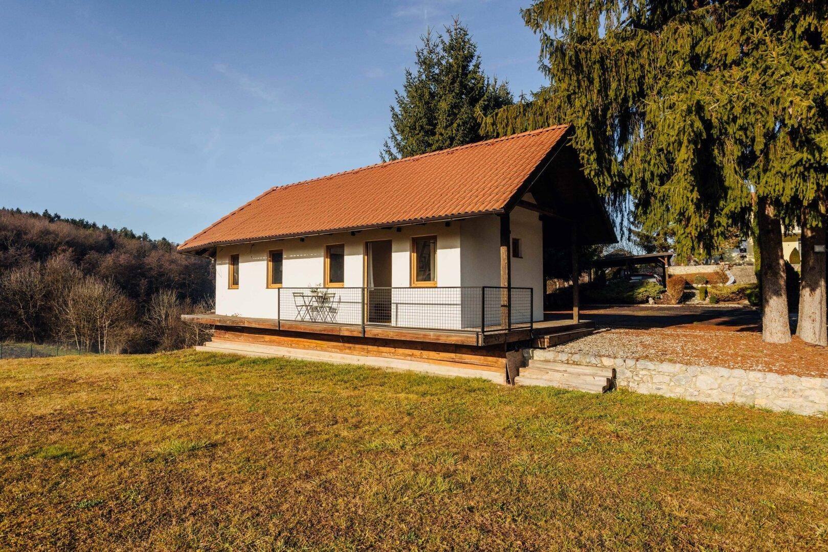 Kleines Gästehaus mit Terrasse und rotem Ziegeldach in ländlicher Umgebung.