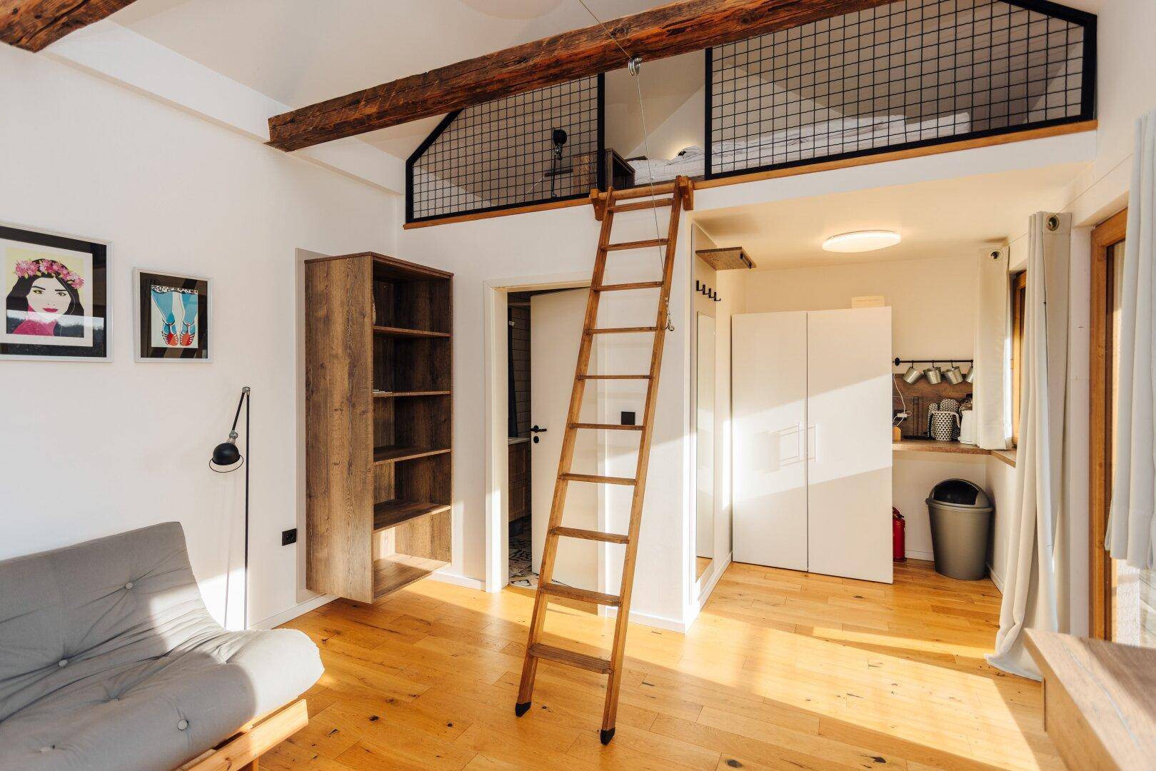 Heller Wohnbereich im Gästehaus mit Hochbett, Holzbalken und viel Tageslicht.