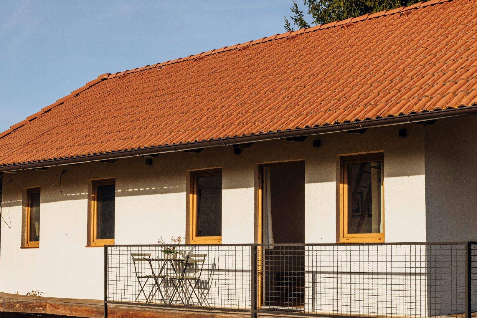 Seitenansicht des Gästehauses mit rotem Ziegeldach und kleiner Terrasse.
