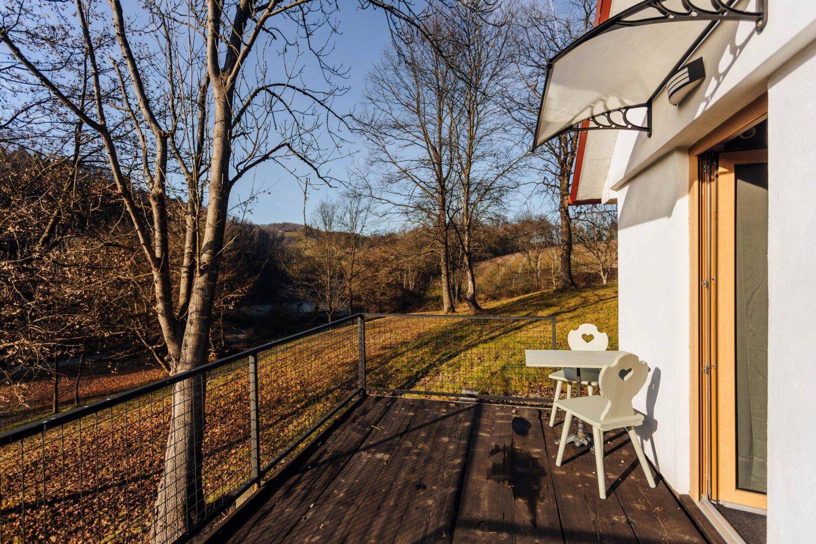 Kleine Holzterrasse mit Metallgeländer und Blick auf die bewaldete Landschaft.