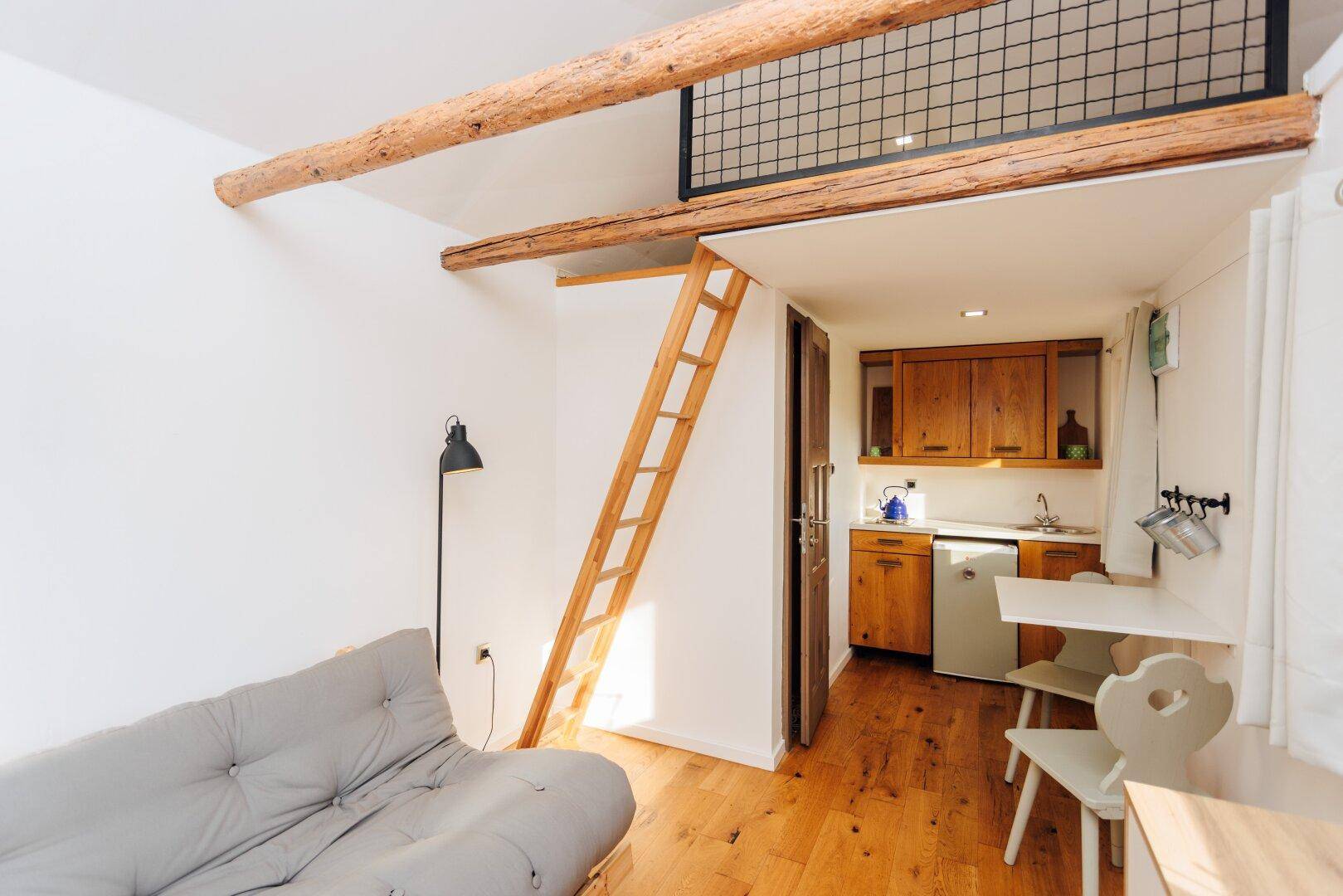 Wohnbereich im Gästehaus mit Küchenzeile, Esstisch und Hochbett im Hintergrund.
