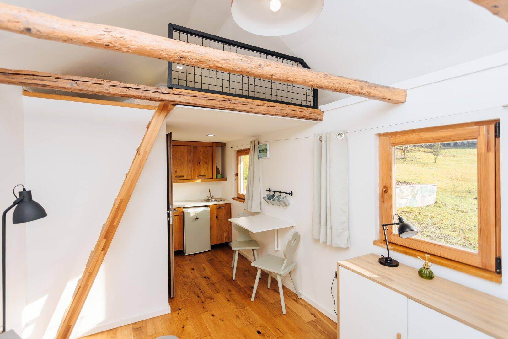 Wohnbereich im Gästehaus mit Küchenzeile, Esstisch und Hochbett im Hintergrund.