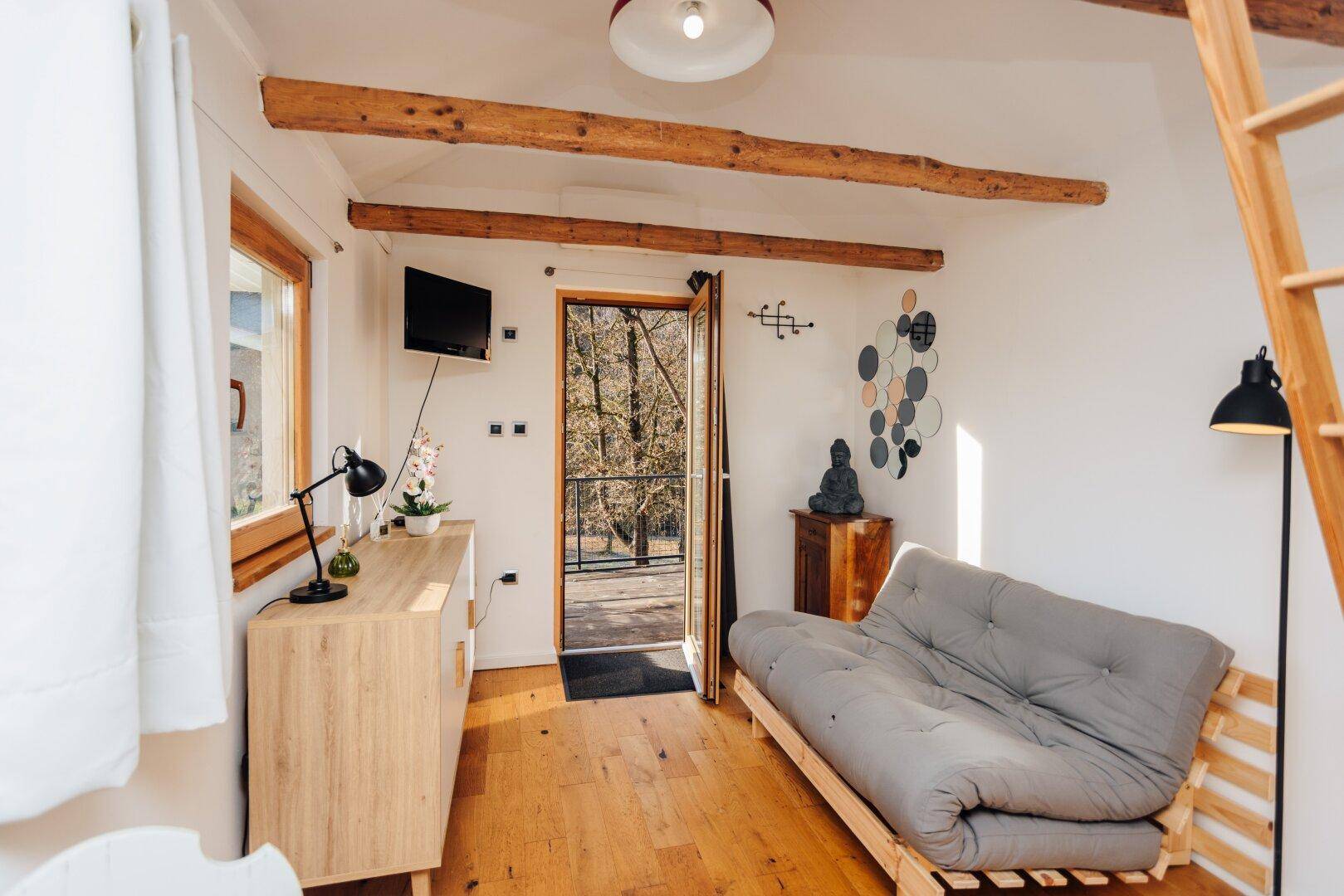 Heller Wohnbereich im Gästehaus mit Sofa, Kommode und Zugang zur Terrasse.