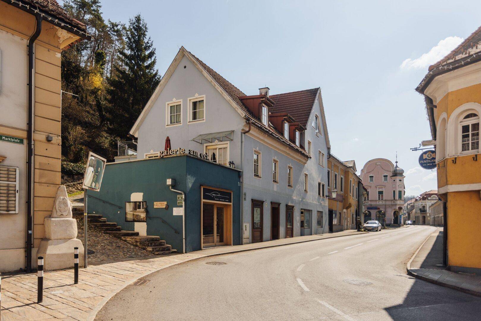 Historisches Gebäude mit hellblauer Fassade und kleiner Terrasse an einer ruhigen Straße.