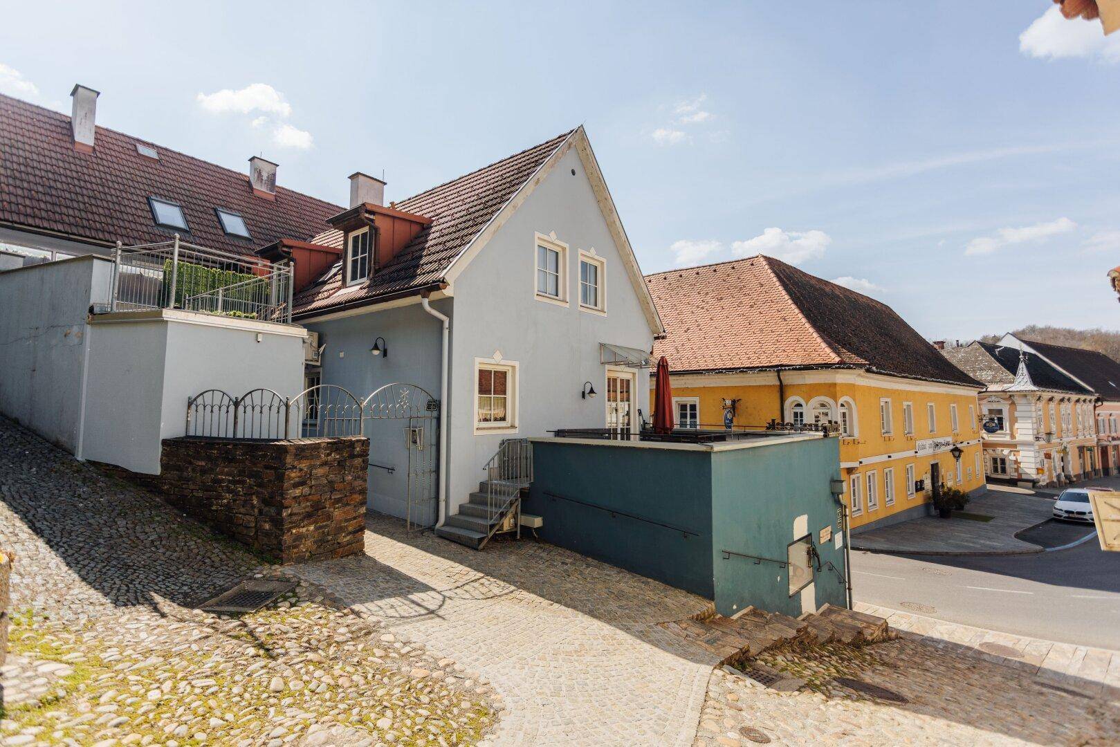 Ansicht des Gebäudes von oben, mit seitlichem Zugang und der Terrasse im Vordergrund.