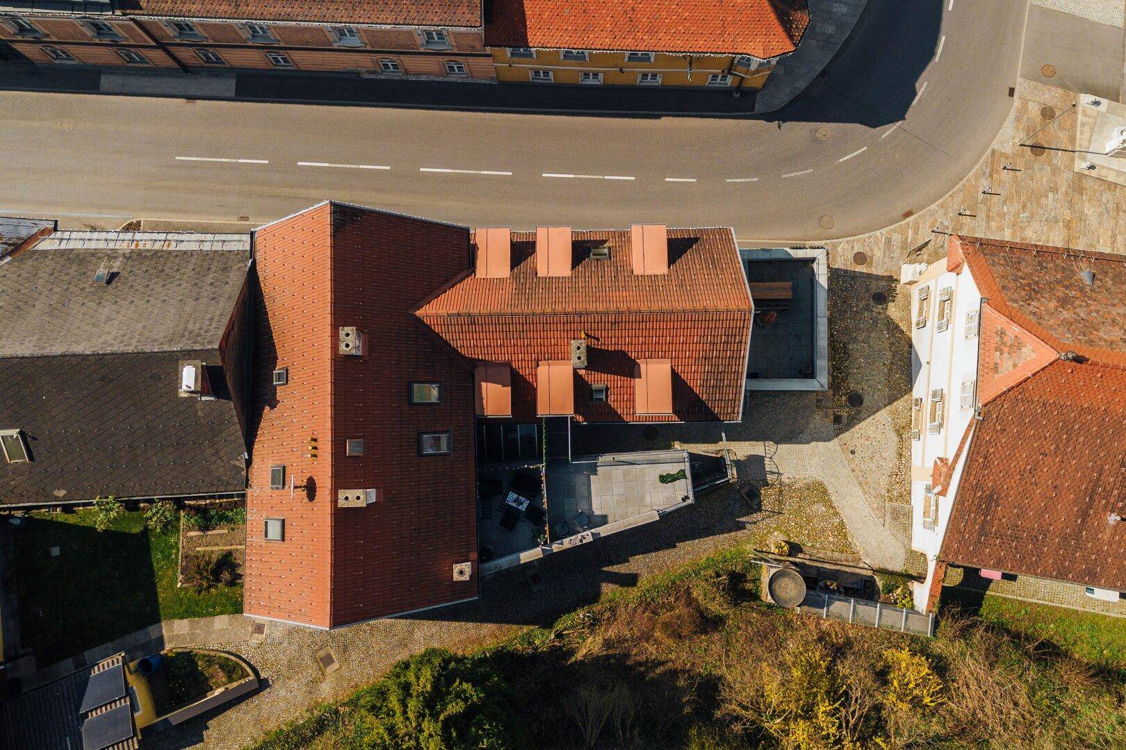Senkrechte Luftaufnahme des Gebäudes mit rotem Ziegeldach und der angrenzenden Terrasse.