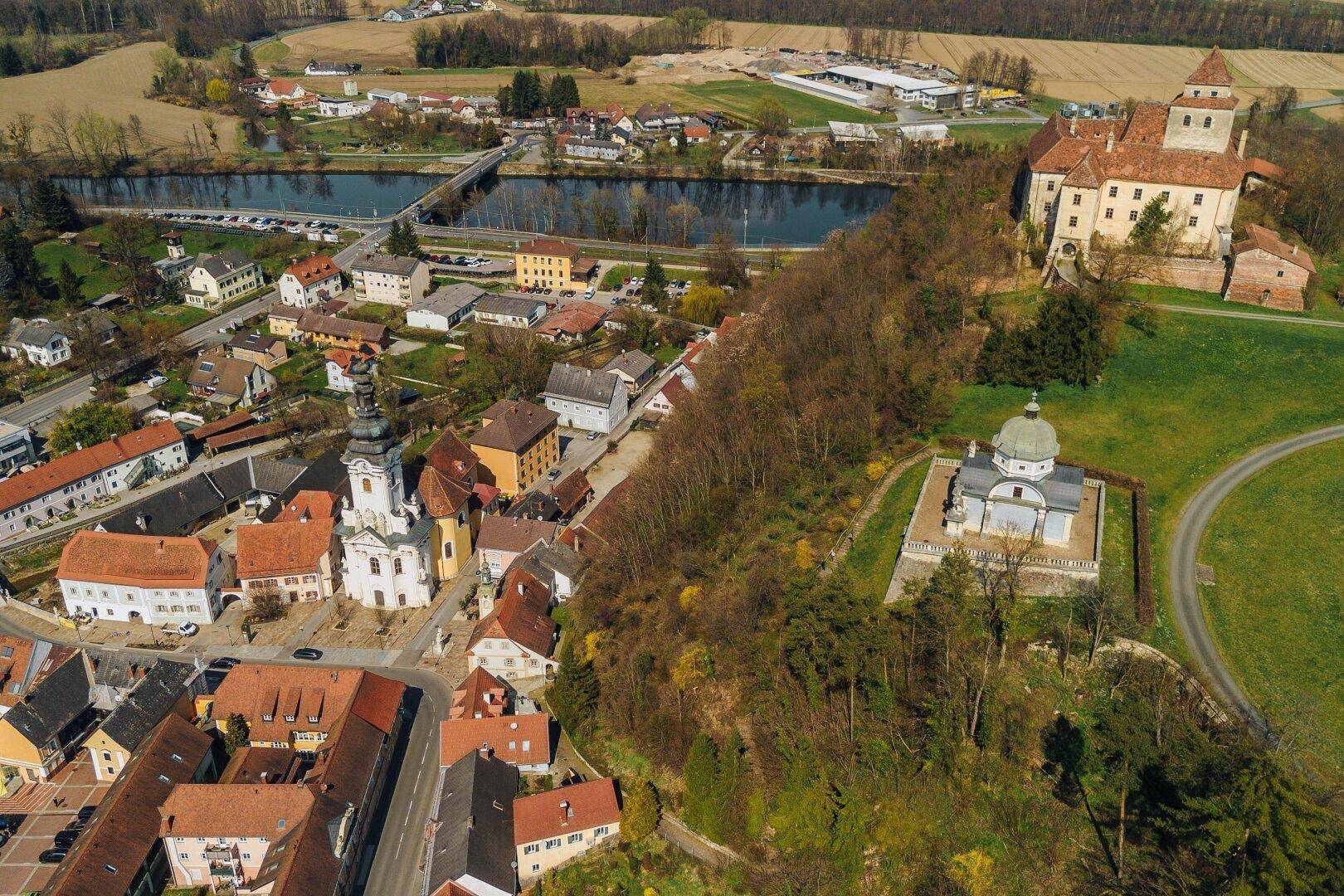Weitläufige Luftaufnahme der Stadt mit Fluss, Burg und der umliegenden grünen Landschaft.