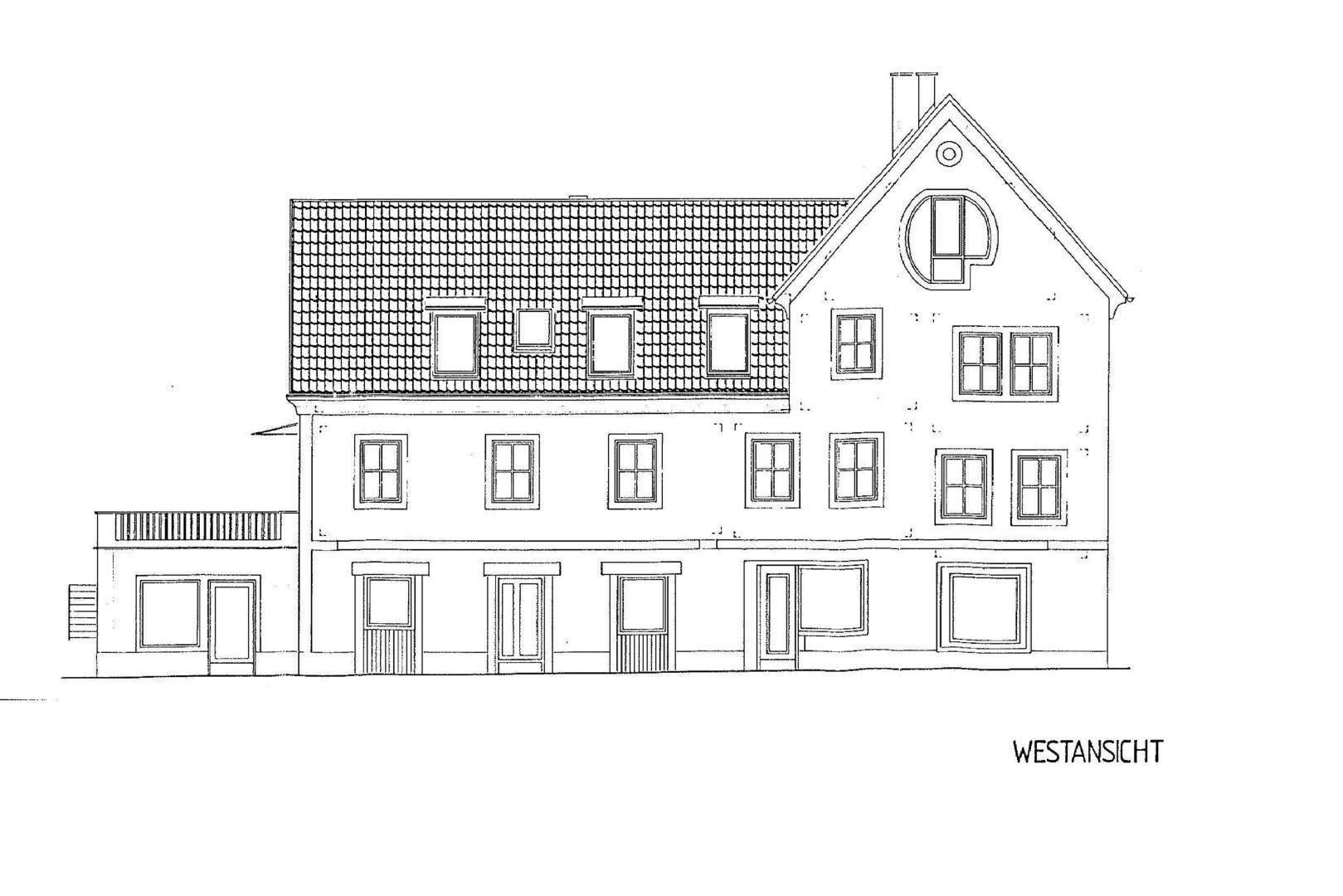 Westansicht des Gebäudes mit vielen Fenstern, einem Balkon und einem markanten Giebel.