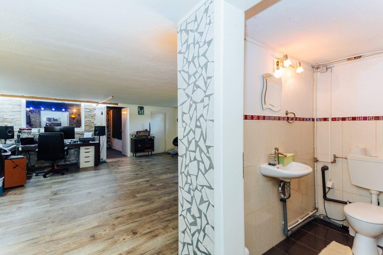 Einfaches Gäste-WC im Kellerbereich mit Waschbecken und Toilette, funktional eingerichtet.