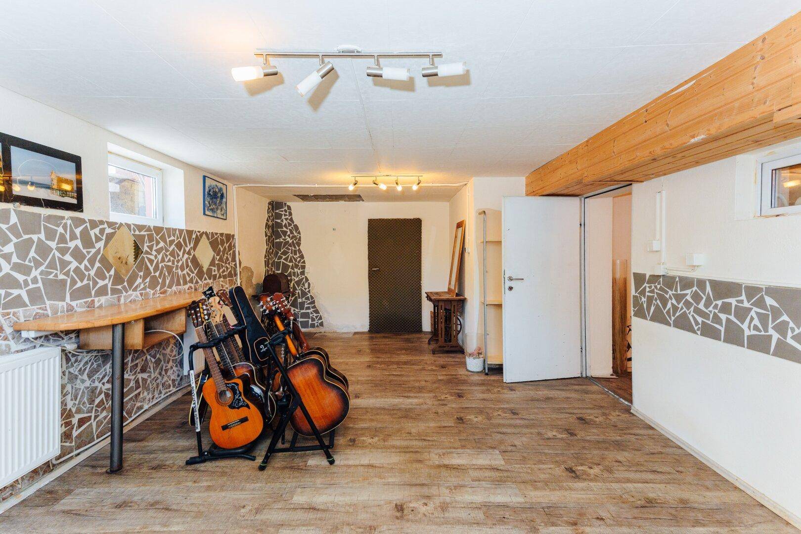 Vielseitiger Kellerraum mit Laminatboden, Holzbalken und Gitarren, ideal für Hobbys oder Lagerung.