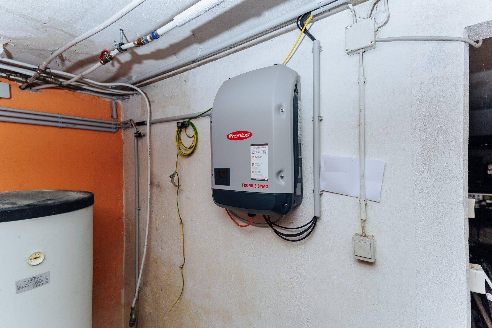 Technikraum mit Wechselrichter für Photovoltaikanlage und Warmwasserspeicher, funktional und aufgeräumt.