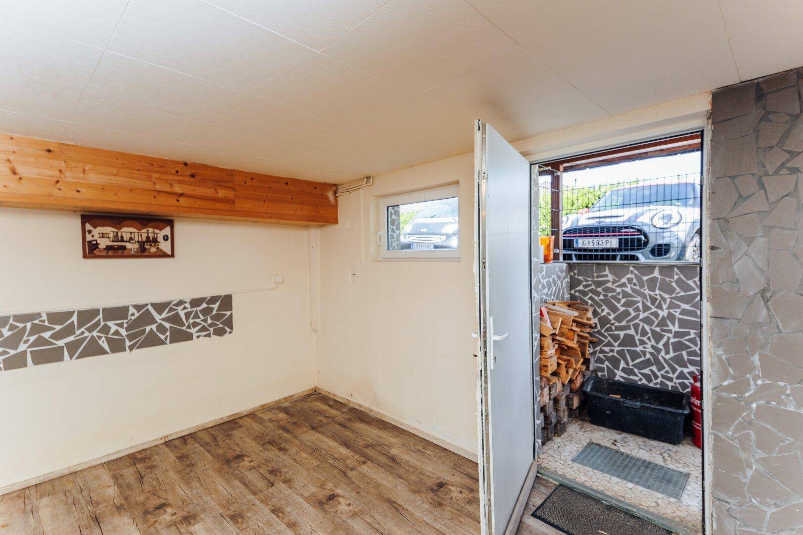 Lagerraum im Keller mit Holzbalken und Zugang zum Außenbereich, ideal für Brennholz.